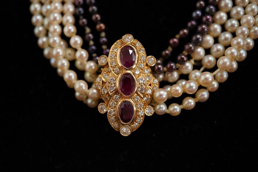 A cultured pearl, ruby and diamond necklace, the clasp set with oval rubies and brilliant-cut diamonds, to a six-strand torsade necklace of cultured pearls of black and white tints, necklace length 61cm, clasp length 2.5